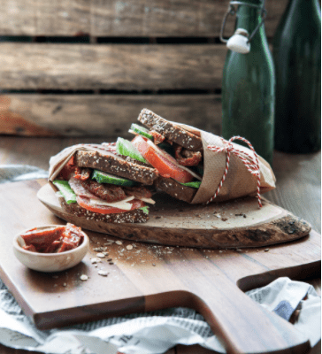 image of sandwich wrapped in bucher's paper on a wooden cutting board