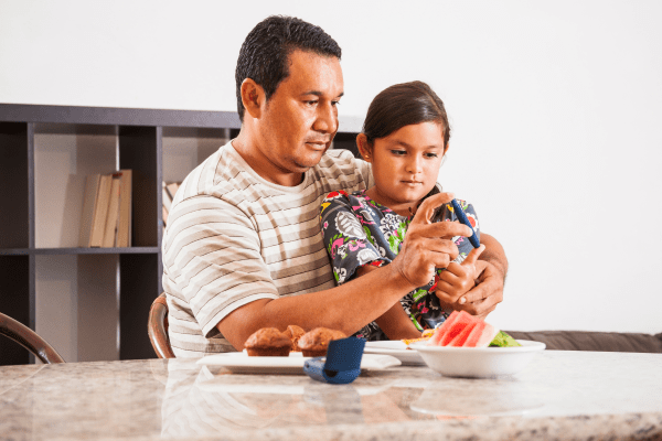 father helping son with diabetes glucose monitor