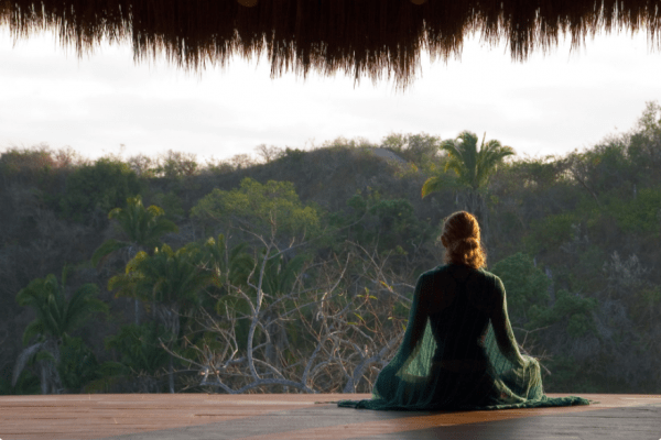 woman meditating in jungle setting, facing away