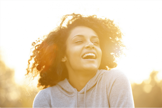 curly-haired woman laughing with golden glow around her